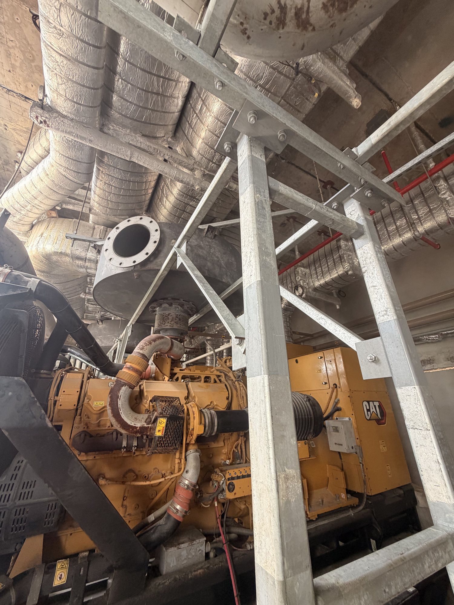 Galvanized-steel generator exhaust support structure installed around existing equipment and silencers