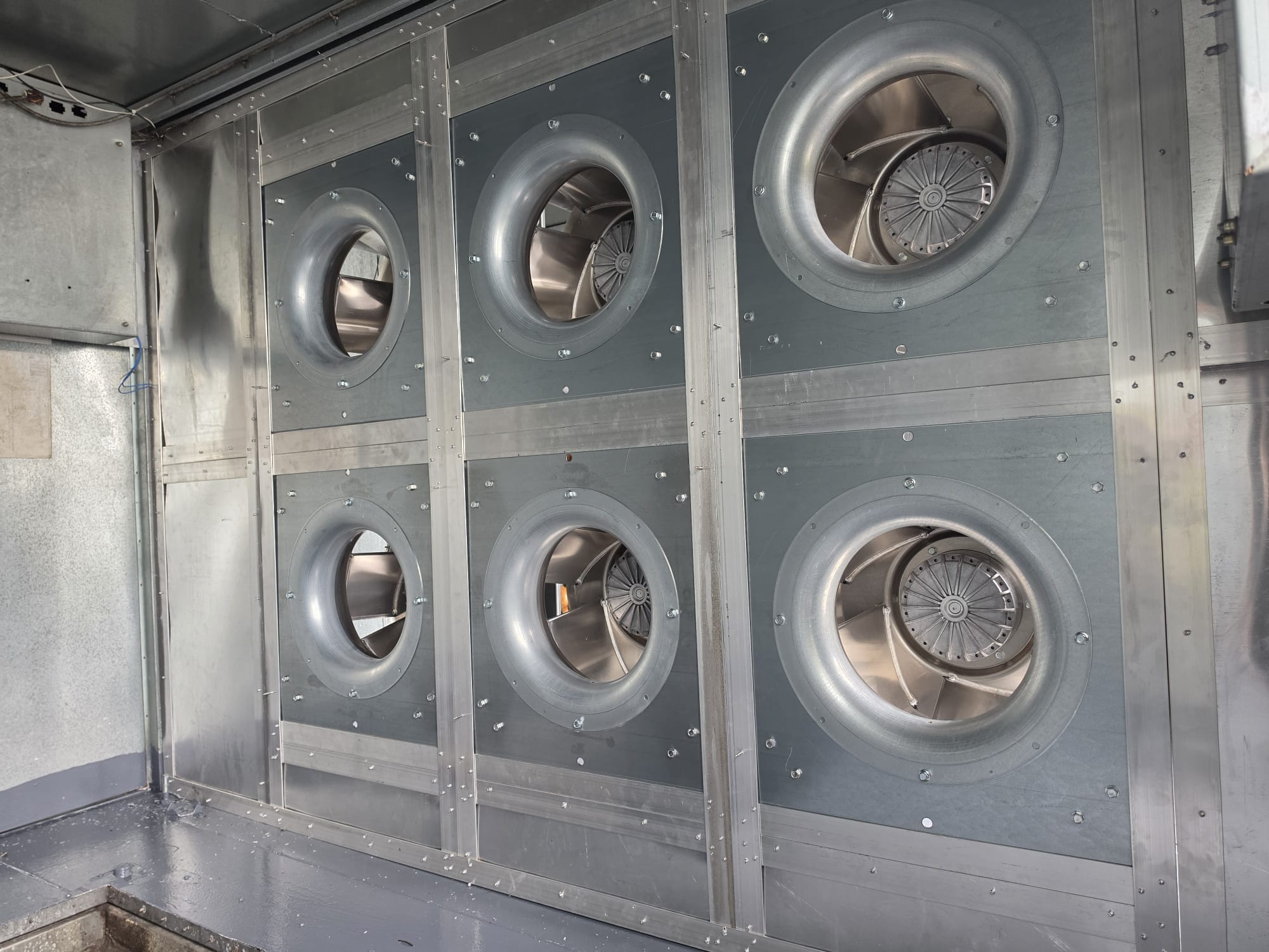 Completed galvanized-steel support wall with six EC plug fans installed inside an air-handling unit